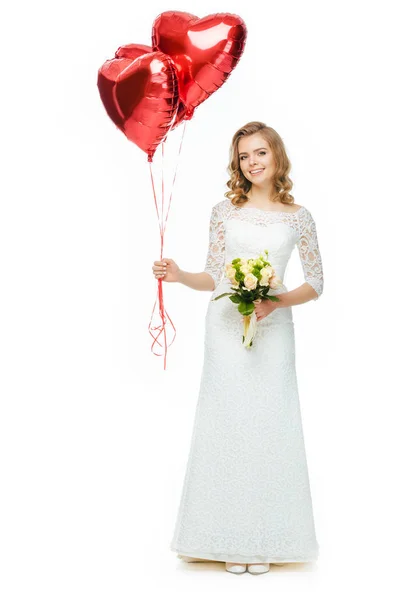 Beautiful bride in wedding dress with heart shaped balloons and wedding bouquet isolated on white — Stock Photo