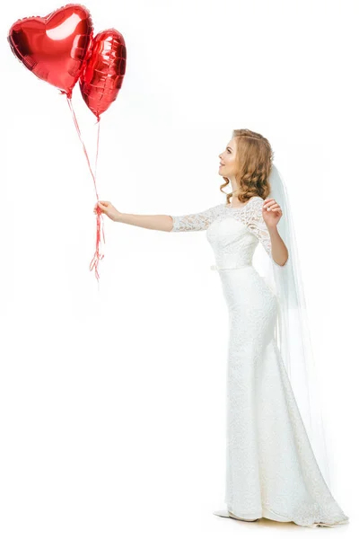 Beautiful bride in wedding dress with heart shaped balloons isolated on white — Stock Photo