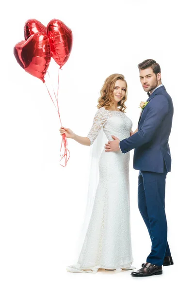 Pareja de boda con globos rojos en forma de corazón aislados en blanco - foto de stock