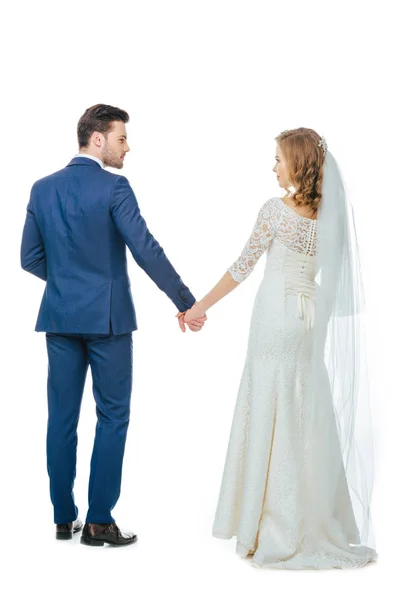 Vista posterior de la hermosa pareja de boda cogida de la mano aislada en blanco - foto de stock