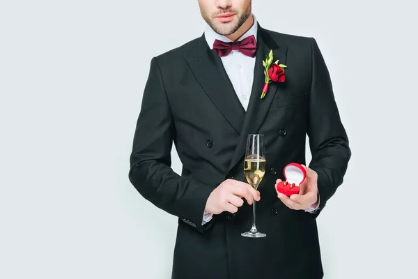 Cropped shot of groom with glass of champagne and wedding ring isolated on grey — Stock Photo