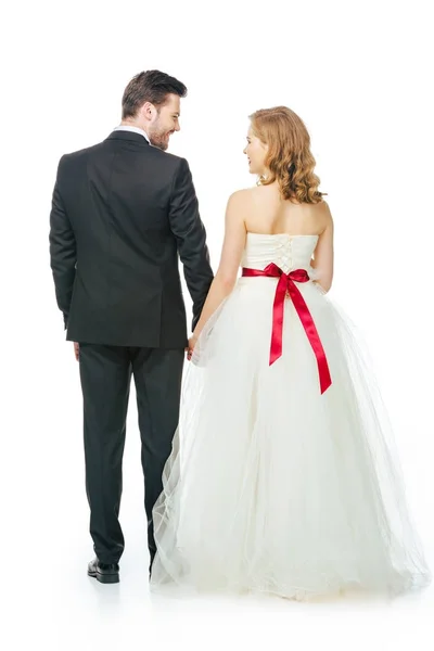 Visão traseira da noiva e noivo segurando as mãos isoladas no branco — Fotografia de Stock