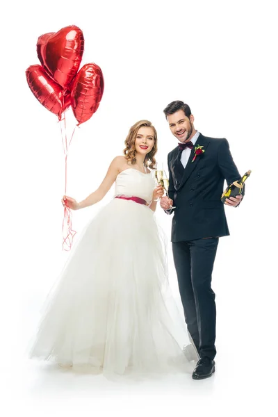 Pareja de boda con globos en forma de corazón rojo y champán aislado en blanco - foto de stock