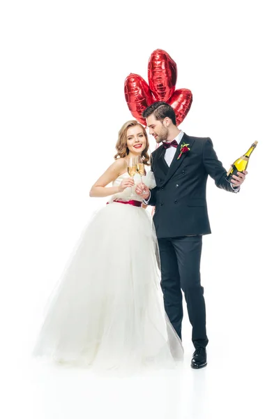 Hochzeitspaar mit roten herzförmigen Luftballons und Champagner auf weißem Grund — Stockfoto