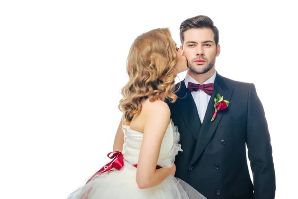 Beautiful bride kissing young groom in suit isolated on white — Stock Photo