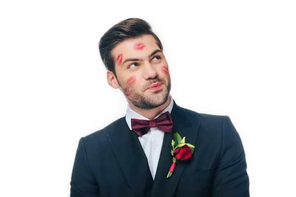 Retrato de novio guapo en traje con lápiz labial rojo en la cara aislado en blanco - foto de stock