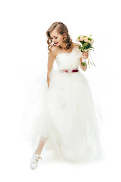 Novia sonriente en hermoso vestido de novia con flores en la mano aislado en blanco - foto de stock