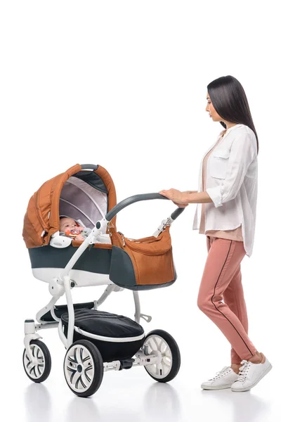 Mujer joven mirando bebé en carro de bebé aislado en blanco - foto de stock