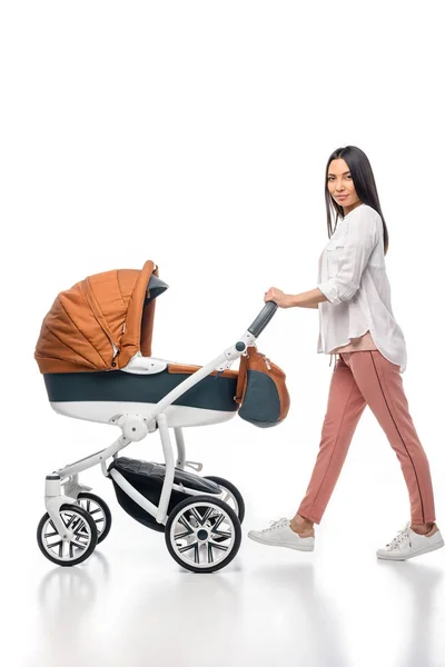 Side view of young woman with infant baby in baby carriage isolated on white — Stock Photo