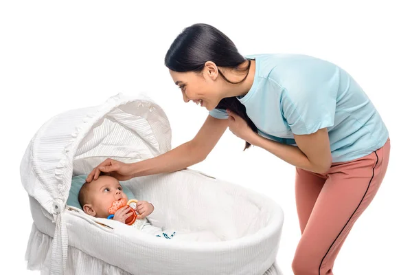 Portrait of young woman and infant baby in crib isolated on white — Stock Photo