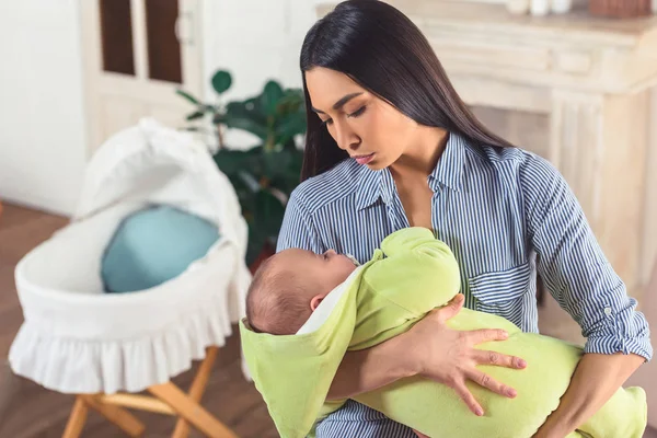 Ritratto della giovane madre che tiene il piccolo bambino in mano a casa — Foto stock