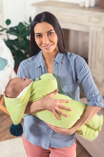 Porträt einer jungen Mutter, die ihr kleines Baby zu Hause in den Händen hält — Stockfoto