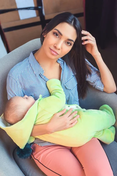 Hermosa madre con bebé bebé descansando en silla de brazo en casa - foto de stock