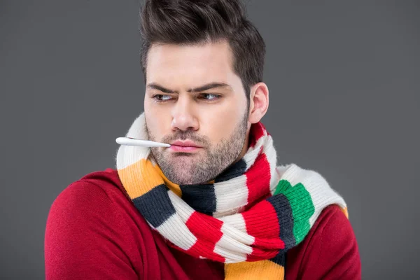 Ill man with temperature in warm scarf, isolated on grey — Stock Photo