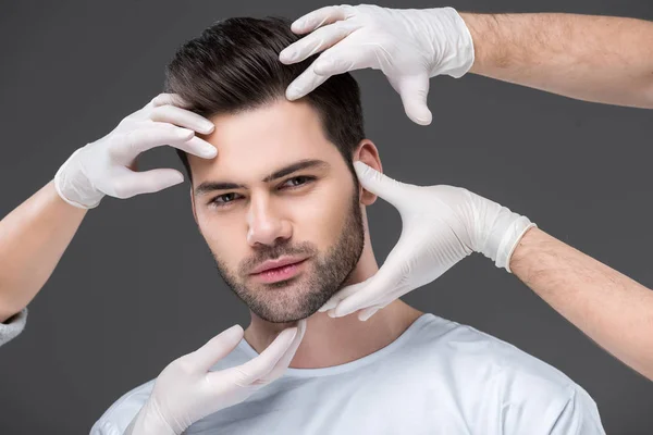 Bearded handsome man and doctors hands, isolated on grey, skin care concept — Stock Photo
