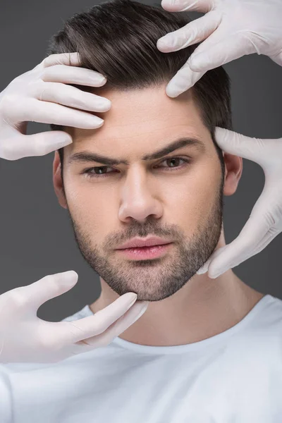 Hombre barbudo y médicos manos, aislado en gris, el concepto de cuidado de la piel - foto de stock