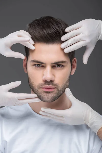 Hombre guapo y médicos manos, aislado en gris, el concepto de cuidado de la piel - foto de stock