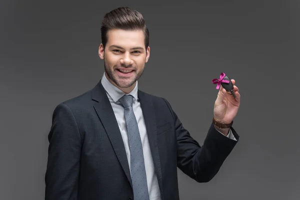 Smiling businessman holding car key, isolated on grey — Stock Photo