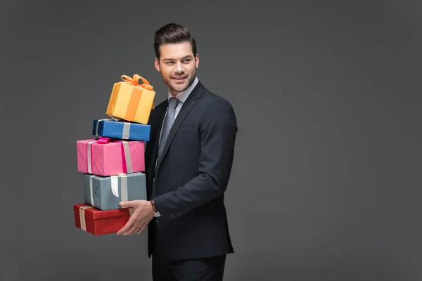 Bearded man holding gift boxes, isolated on grey — Stock Photo