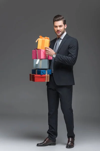 Красивий бородач тримає подарункові коробки, ізольовані на сірому — стокове фото