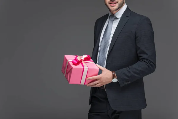 Cropped view of man in suit holding present, isolated on grey — Stock Photo