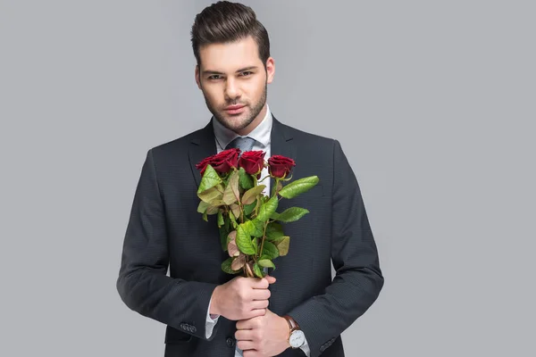 Elegant man holding bouquet of red roses, isolated on grey — Stock Photo