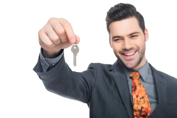 Smiling realtor holding house key, isolated on white — Stock Photo