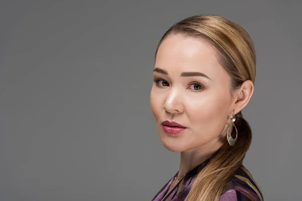 Primer plano retrato de hermosa mujer kazakh elegante mirando a la cámara aislada en gris - foto de stock