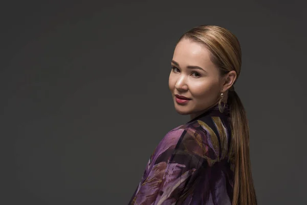 Retrato de la hermosa mujer kazakh sonriendo a la cámara aislada en gris - foto de stock