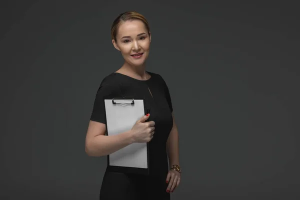Beautiful kazakh businesswoman holding clipboard and smiling at camera isolated on grey — Stock Photo