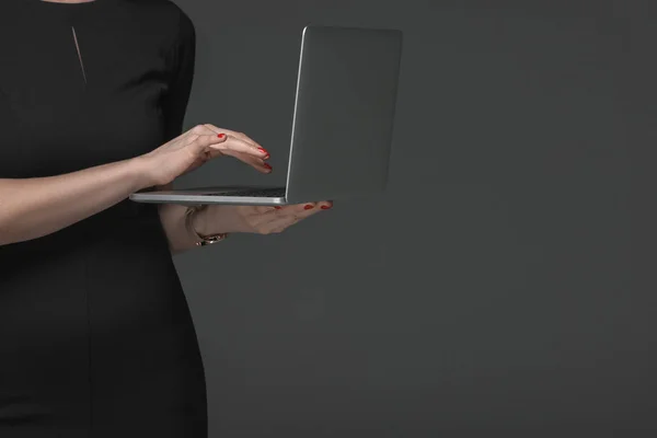 Close-up partial view of woman in black dress using laptop isolated on grey — Stock Photo