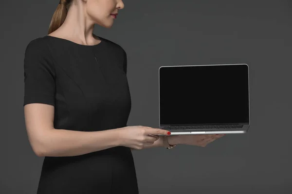 Abgeschnittene Aufnahme einer attraktiven Frau mit Laptop und leerem Bildschirm isoliert auf grau — Stockfoto