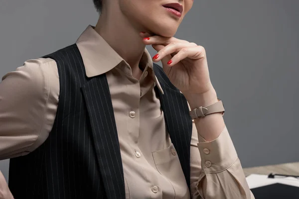 Tiro recortado de elegante mujer de negocios kazakh con la mano en la barbilla en gris - foto de stock