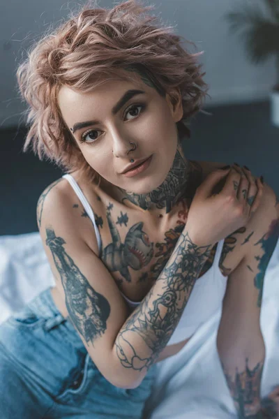 Portrait of tender tattooed girl with pink hair in bedroom — Stock Photo