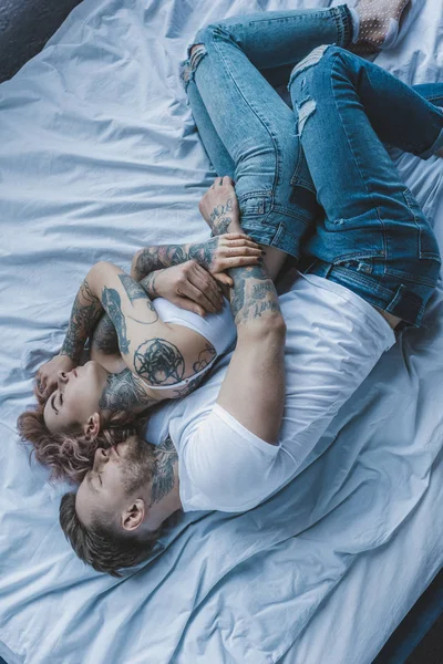 Vista dall'alto della coppia tatuata che abbraccia e dorme sul letto — Foto stock