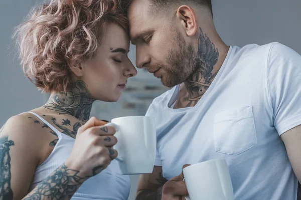 Junges tätowiertes Paar mit Kaffee auf der Stirn am Morgen — Stockfoto