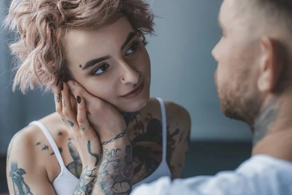 Macio tatuado homem tocando rosto de seu atraente namorada — Fotografia de Stock