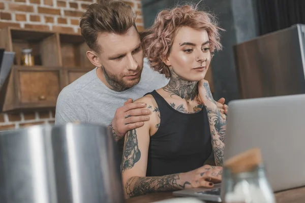 Татуированная пара с помощью ноутбука дома — стоковое фото