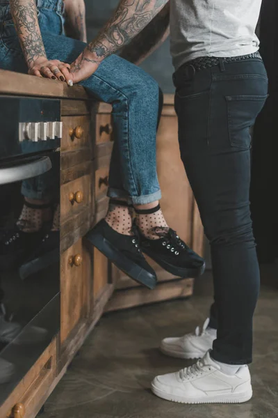 Vista de sección baja de joven pareja tatuada en la cocina - foto de stock