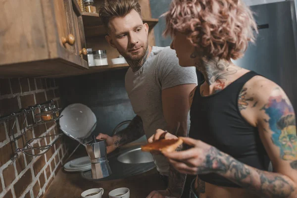Tattooed couple cooking breakfast at kitchen — Stock Photo