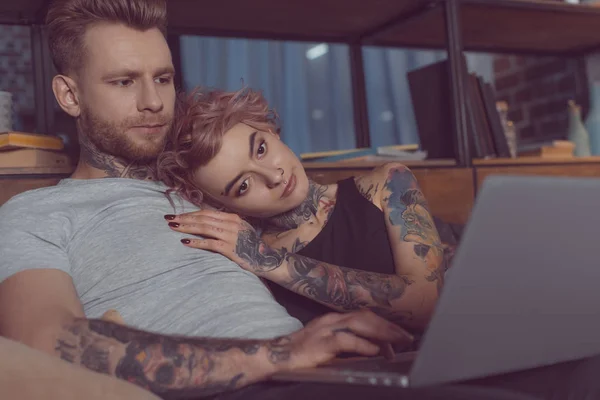 Atractiva pareja caucásica relajarse y usar el ordenador portátil en casa - foto de stock