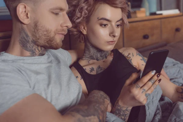 Atraente casal caucasiano usando smartphone em casa — Fotografia de Stock