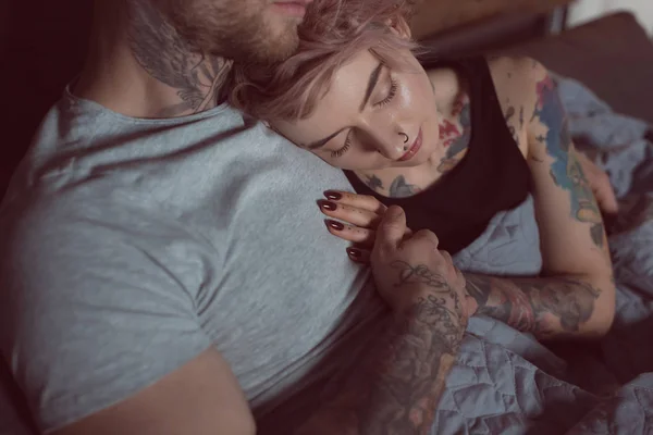 Beautiful tattooed girl sleeping on her boyfriend at home — Stock Photo