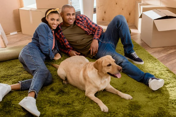 Couple afro-américain avec chien labrador déménageant dans un nouvel appartement — Photo de stock