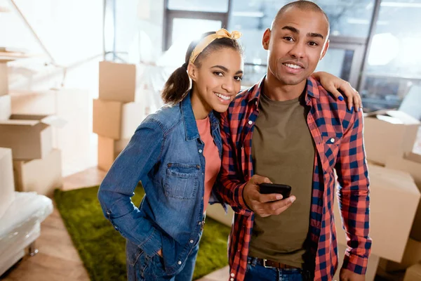 Glückliches afrikanisch-amerikanisches Paar mit Smartphone in neuer Wohnung — Stockfoto