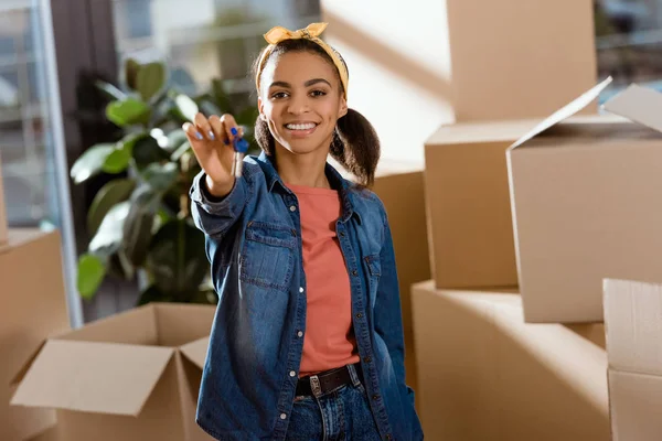 Young smiling african american girl holding keys from new home — Stock Photo