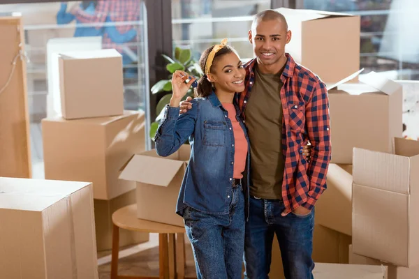 Pareja afroamericana abrazando y sosteniendo llaves de un nuevo hogar - foto de stock