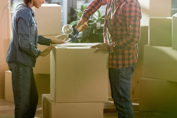 Cropped view of african american couple packing cardboard box to move in new home — Stock Photo