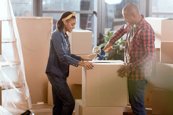 Boîte en carton d'emballage de couple afro-américain pour se déplacer dans un nouvel appartement — Photo de stock