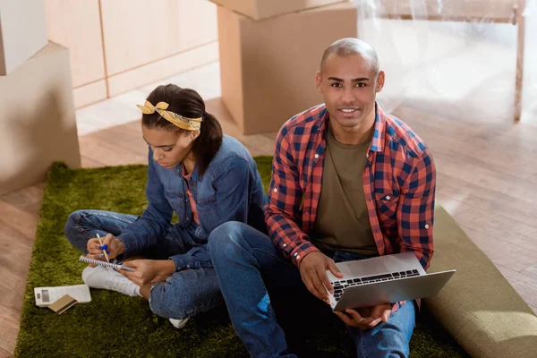 Africano americano pareja compras en línea con tarjeta de crédito y portátil en nuevo hogar - foto de stock